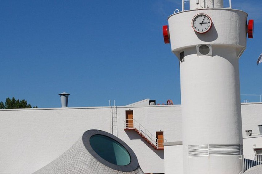 A white cylindrical tower with a clock, a round window, and a ladder leading to a door. 4
