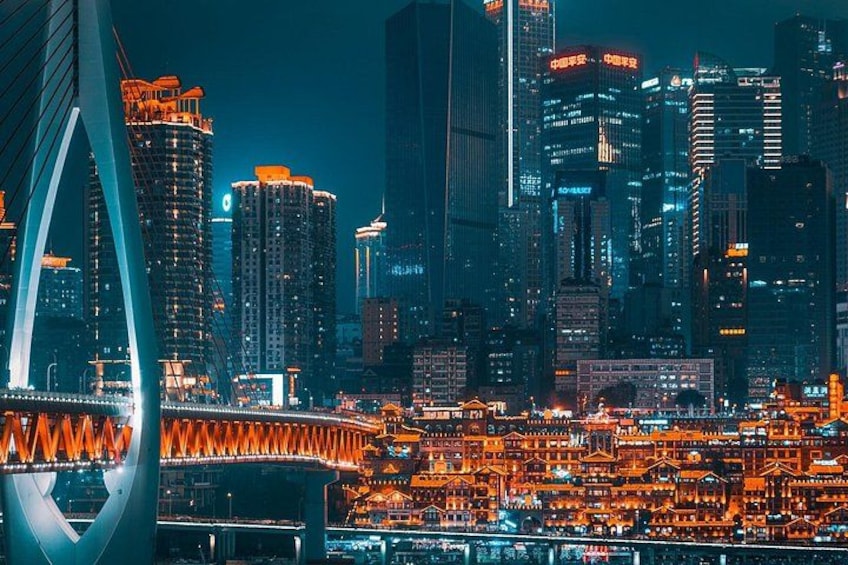A cityscape at night with illuminated buildings, a bridge, and a river. 1