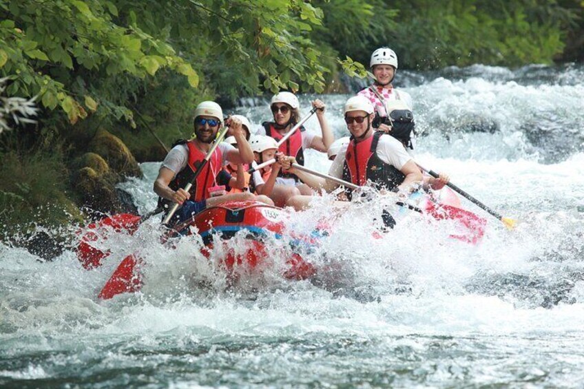 Un groupe de personnes à bord d’un radeau rouge naviguant sur une rivière. 2