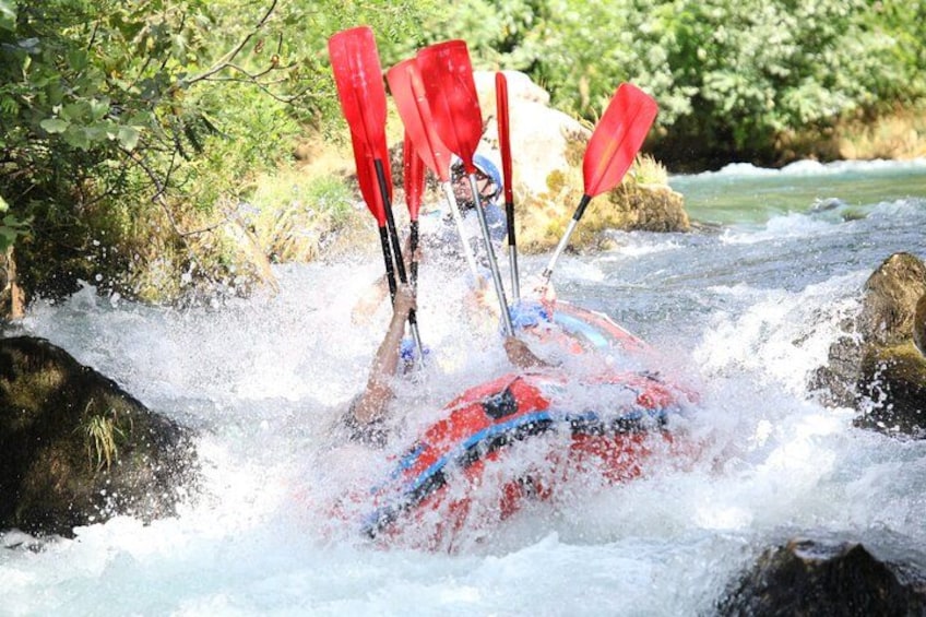 Une personne pratiquant le kayak sur une rivière à courant rapide, entourée de rochers et de végétation. 1