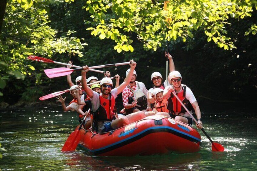 A group of people in a red inflatable raft on a river surrounded by trees. 3
