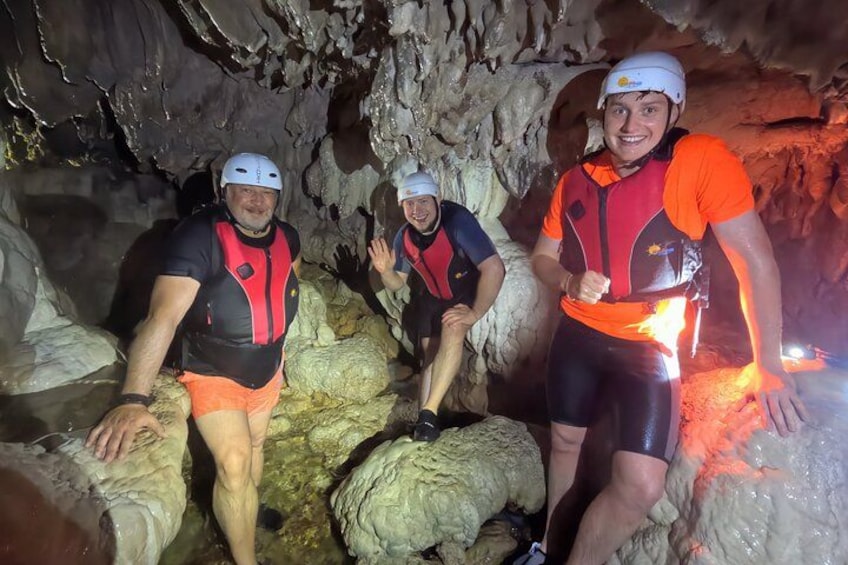 Trois personnes se trouvent dans une grotte, portant des casques et des gilets de sauvetage. 3