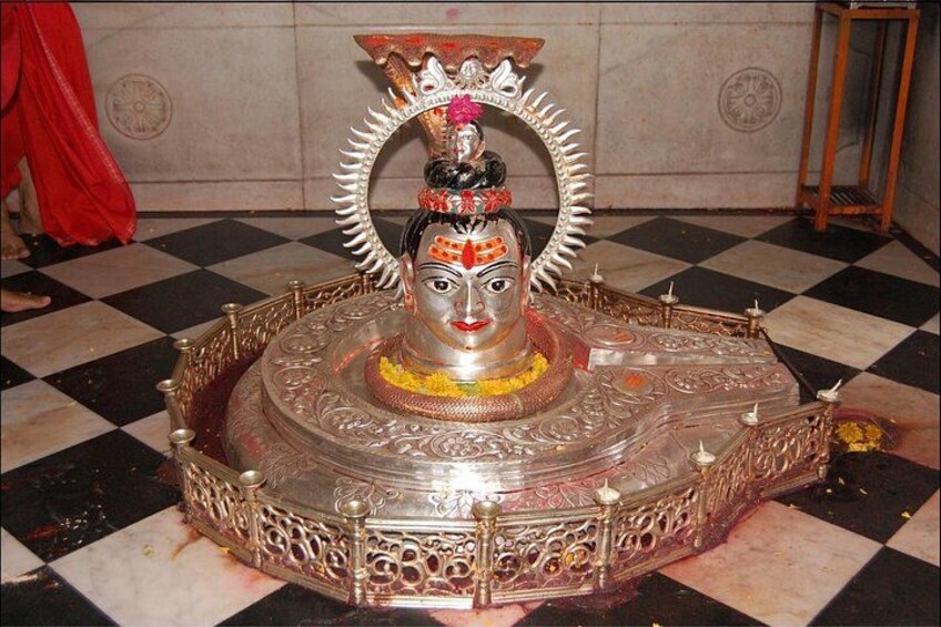 A statue with intricate designs and a circular base, set against a checkered floor. 2
