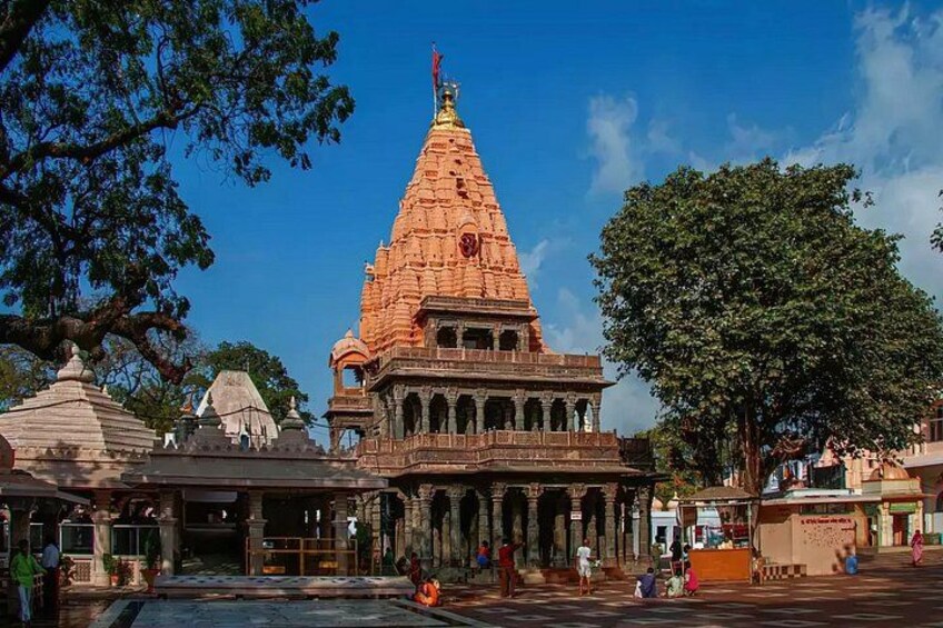 A temple with a large spire, a courtyard, and a tree. 3