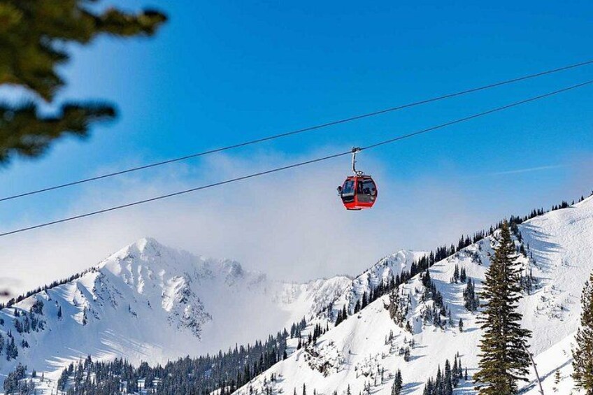 A cable car ascending a snow-covered mountain with a clear sky. 3