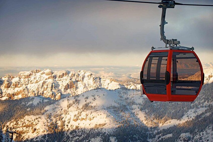 A red cable car suspended over a snowy mountain landscape. 1