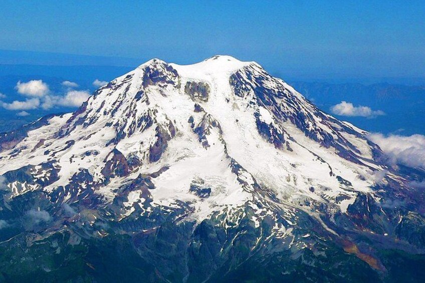 A snow-capped mountain with rugged terrain and a clear blue sky. 5