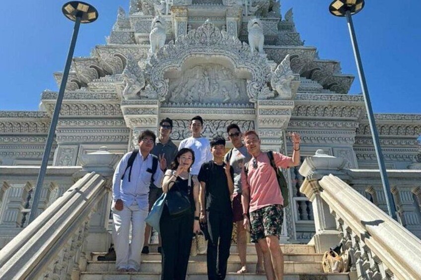 A group of people standing in front of a large, ornate building with intricate carvings and statues. 4
