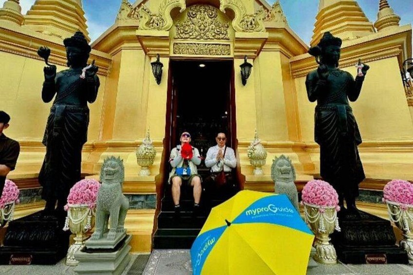 A temple entrance with golden doors, a statue of a deity, and a person sitting on steps. 2