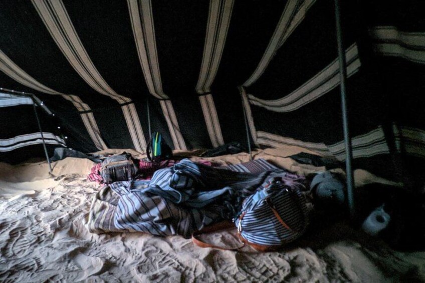 Ein Zelt mit gestreiftem Stoff und einem Schlafsack sowie einem Rucksack auf dem Boden. 2