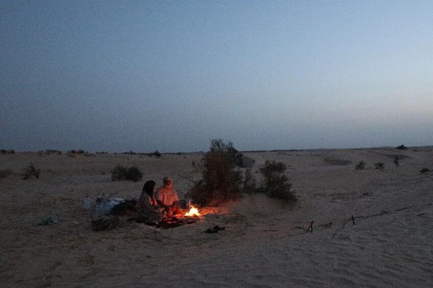 Wüstenlandschaft mit Lagerfeuer und zwei Personen in der Nähe. 3