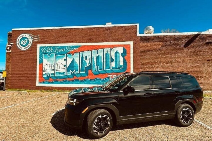 A black SUV parked in front of a mural with the word 'Memphis' and a cityscape. 1