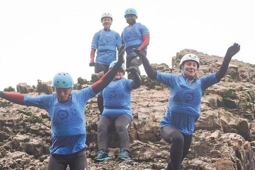 A group of people wearing helmets and blue shirts, standing on rocky terrain. 2
