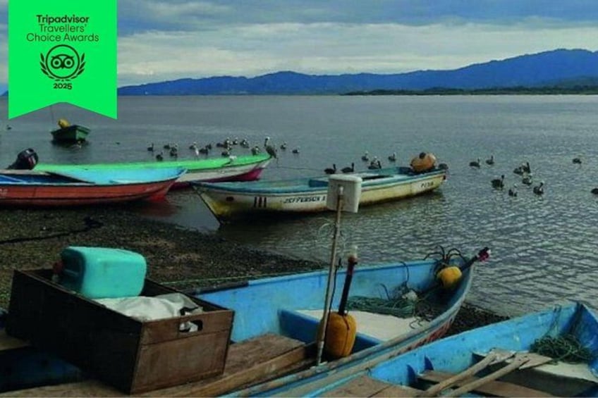 Un lago tranquilo con varias embarcaciones amarradas a la orilla, rodeado de montañas al fondo. 1