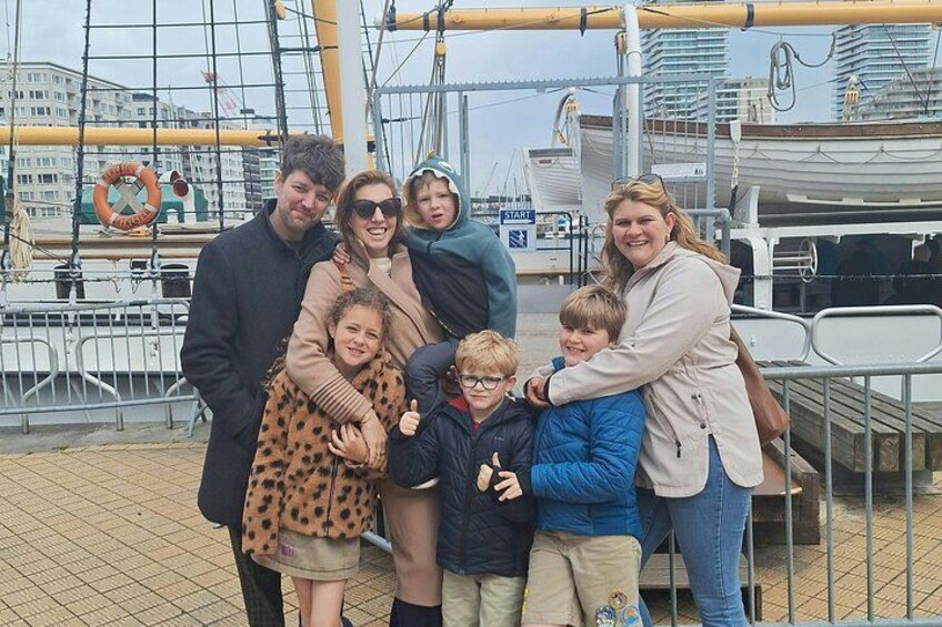Un grupo de personas en un muelle con un barco al fondo. 4