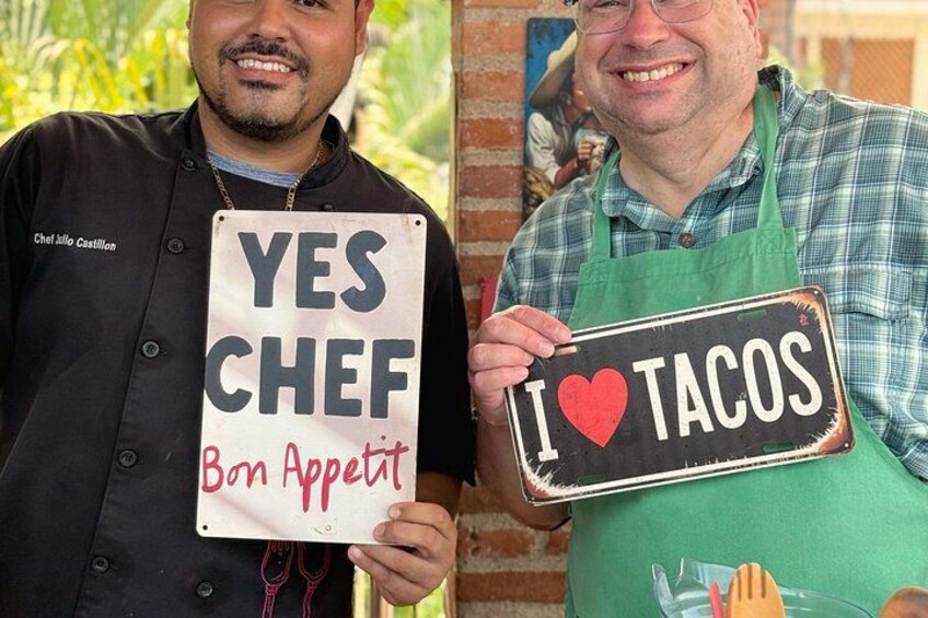 Deux personnes tiennent des pancartes : l’une porte l’inscription « OUI, CHEF, bon appétit » et l’autre, « J’adore les tacos ». 4