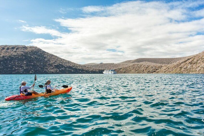 Two people kayaking on a calm lake with mountains in the background. 2