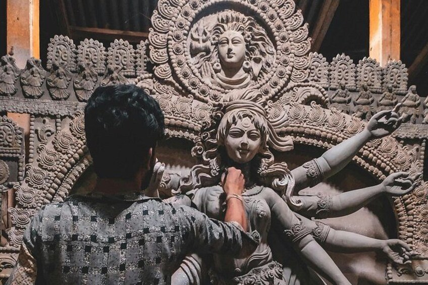 A person working on a detailed stone sculpture with intricate patterns and figures. 5