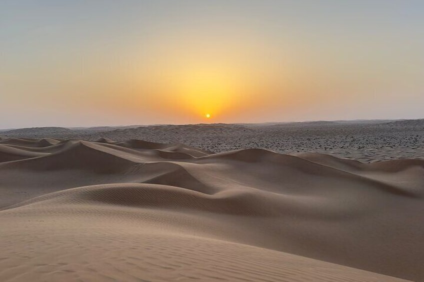 Un paysage désertique avec des dunes de sable et un soleil couchant. 1