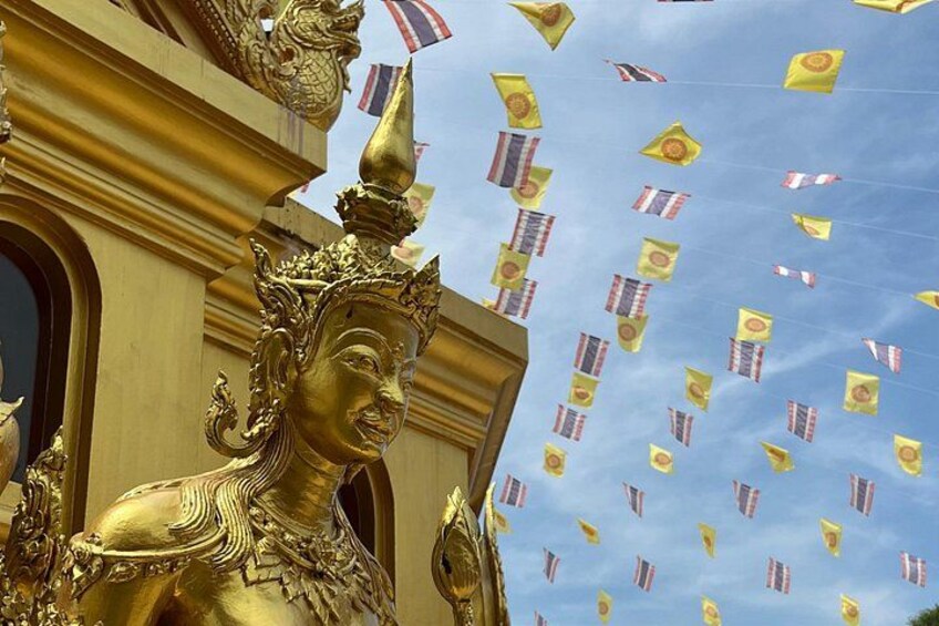 Eine goldene Statue vor einem von Flaggen geschmückten Himmel. 2