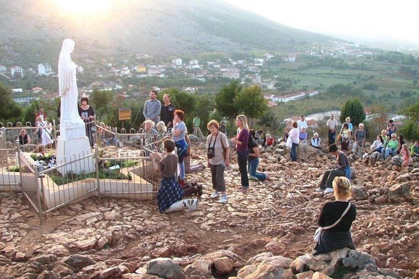 A rocky landscape with a white statue and a fenced area. 3
