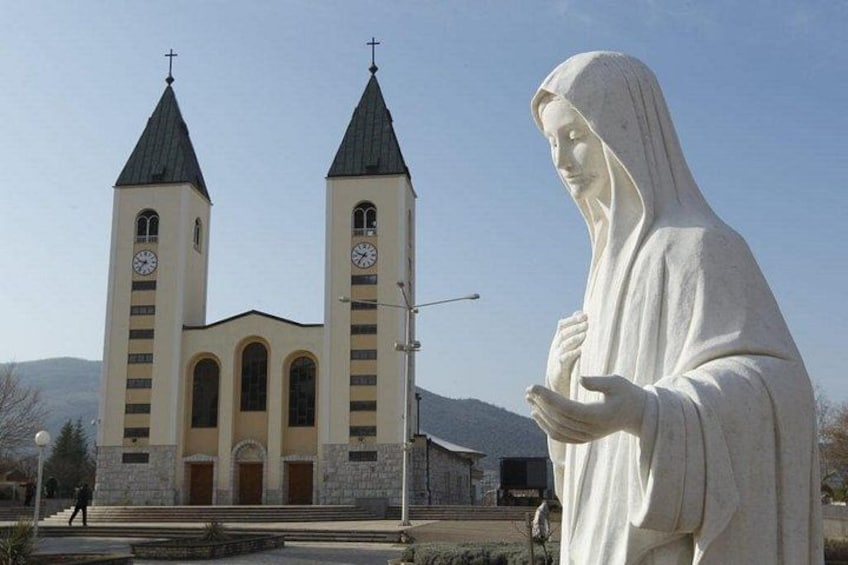 A church with two towers and a statue of a robed figure. 4