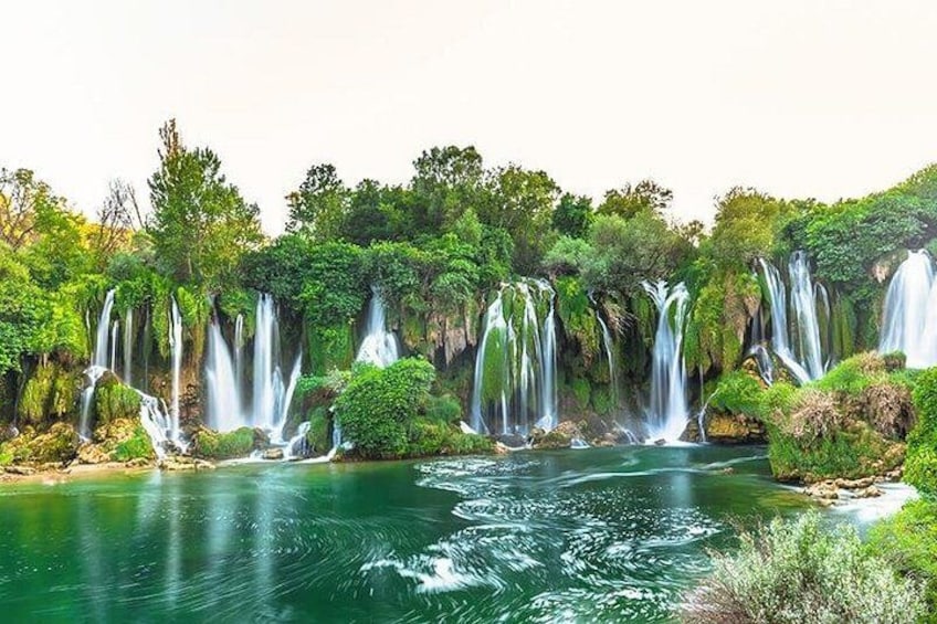 A waterfall cascading over rocks into a river surrounded by lush greenery. 5
