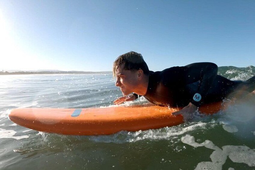 A person lying on a surfboard in the water. 2
