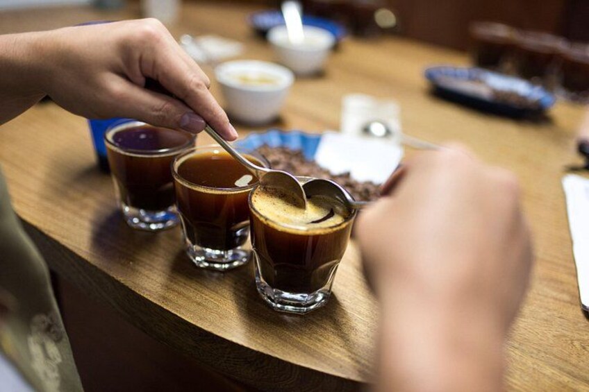 A person stirring coffee in a glass cup on a wooden table. 4