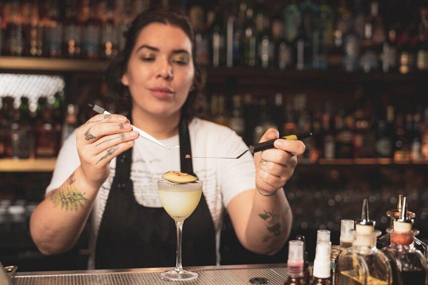 A bartender preparing a cocktail with a lime garnish. 1