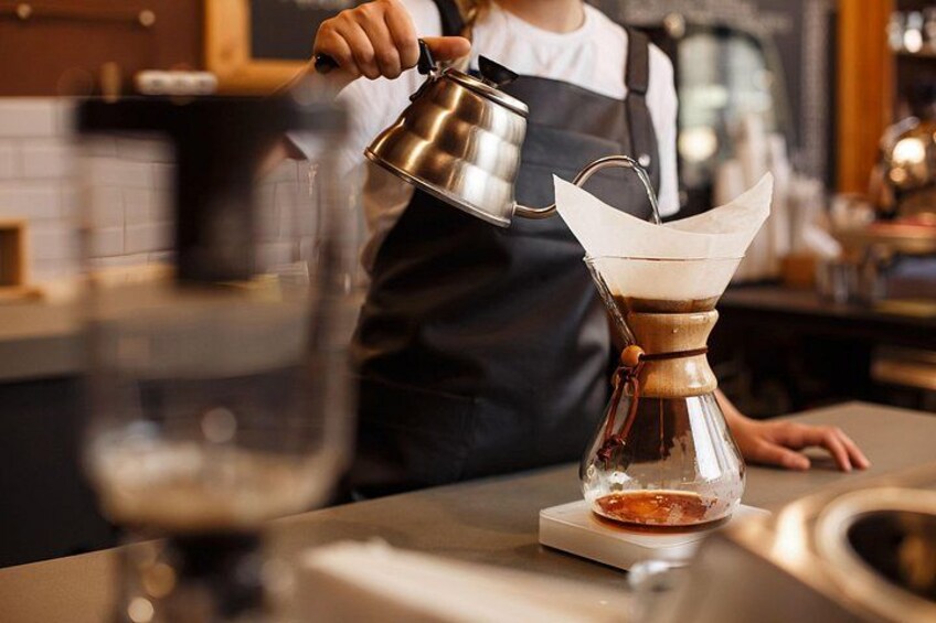 A person pouring liquid from a kettle into a coffee dripper. 2