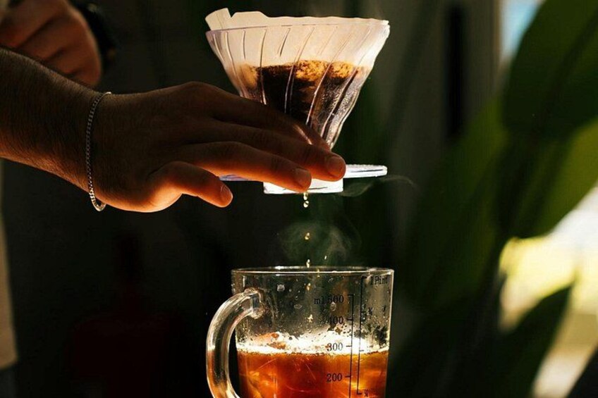 A person pouring a dark liquid from a glass into a measuring cup. 5