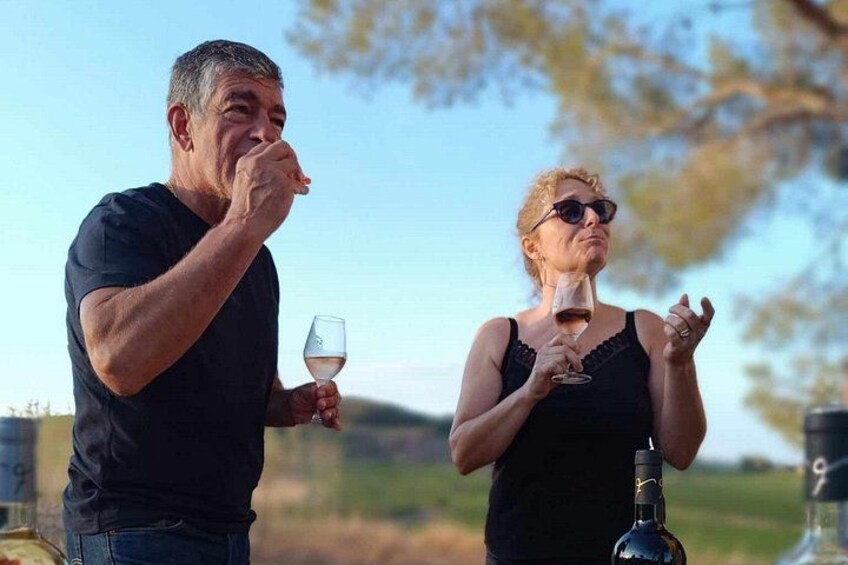 Two people tasting wine outdoors with a bottle and glass visible. 2