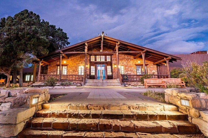 A stone building with a wooden porch, steps leading up to the entrance, and a bench in front. 5