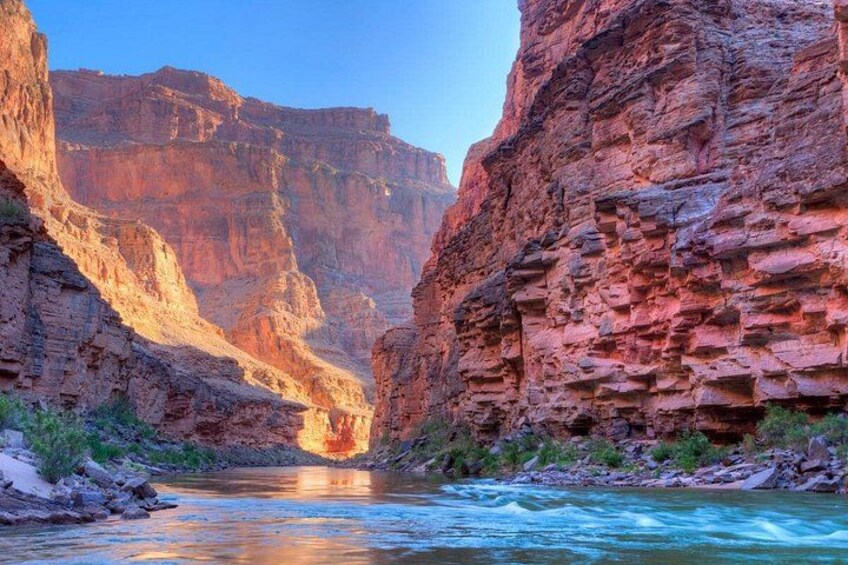 A canyon with a river flowing through it, steep cliffs, and a clear sky. 2