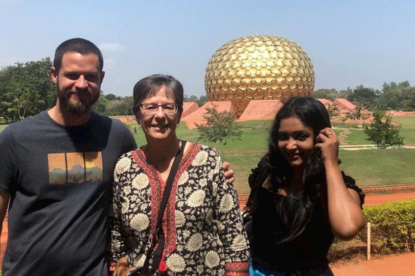 Three people standing in front of a large golden dome structure. 1