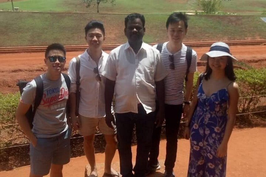 A group of people standing on a dirt path with greenery in the background. 3