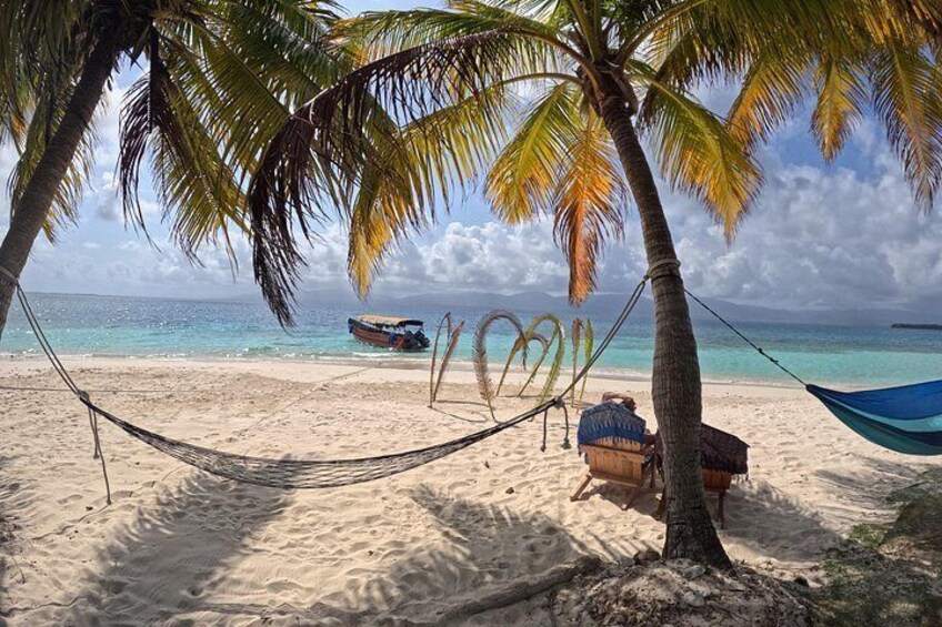 A beach with a hammock, a boat, and a wooden structure. 3