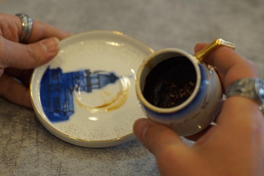 A person holding a ceramic mug with a blue design on a plate. 2
