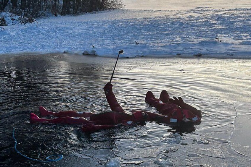 En person ligger på en frusen sjö med skidor och en skidstav. 4