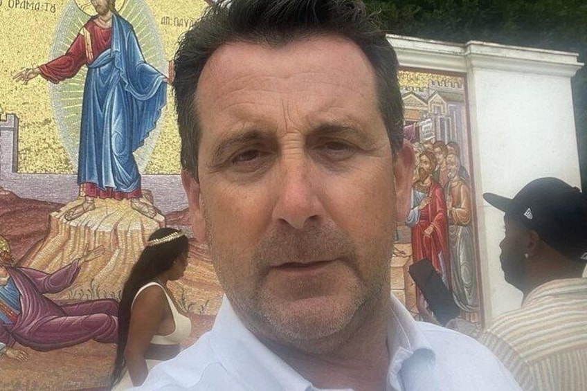 Een man voor een muurschildering met religieuze afbeeldingen. 4