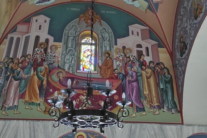 Een religieuze muurschildering met figuren, een centrale figuur op een troon, en een glas-in-loodraam. 3