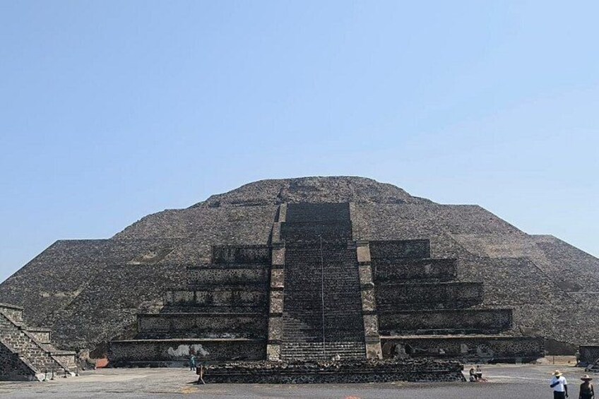 Eine große Pyramidenstruktur mit einer Treppe, die zum Gipfel führt, umgeben von einem flachen Hügel. 2