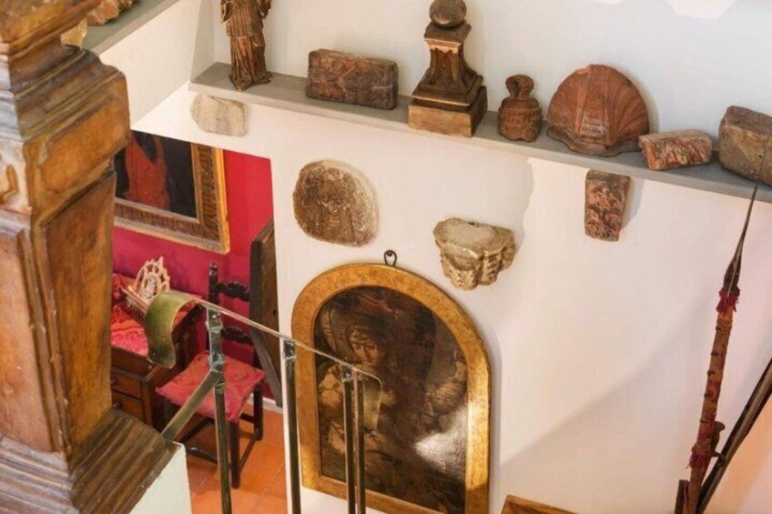 A room with a wooden staircase, a mirror with a framed picture, and various stone and shell decorations on the wall. 4