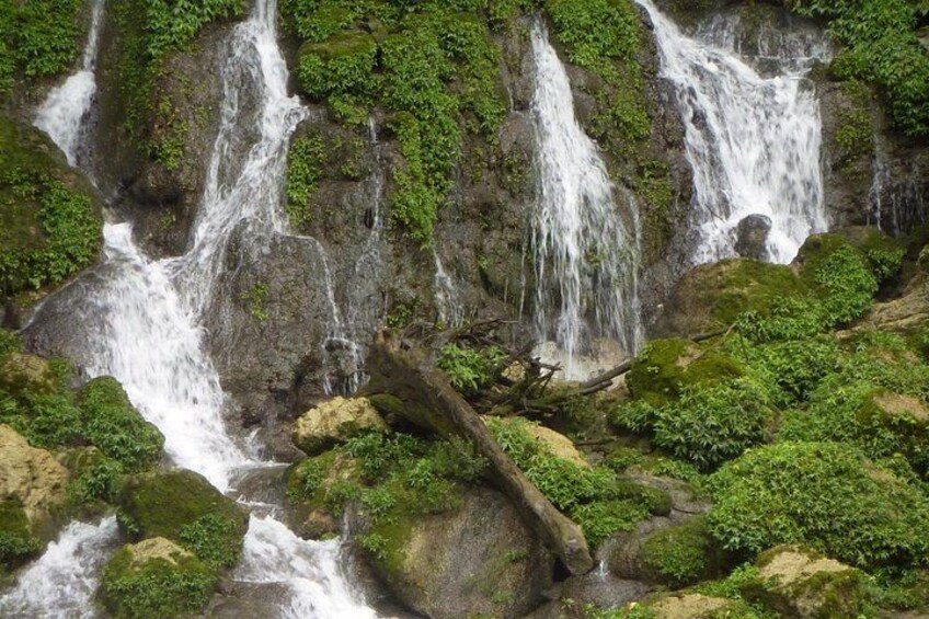 Et vandfald i flere niveauer omgivet af frodig vegetation. 4