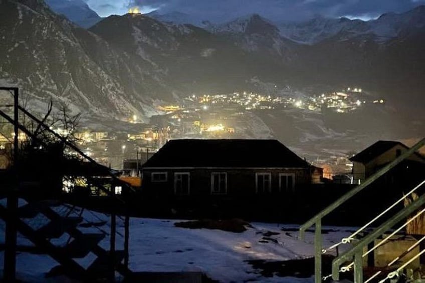 A snow-covered landscape with a town illuminated in the background. 2