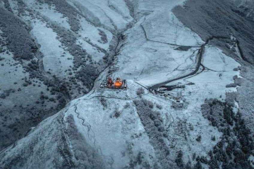 A helicopter in a snowy valley with a river. 5
