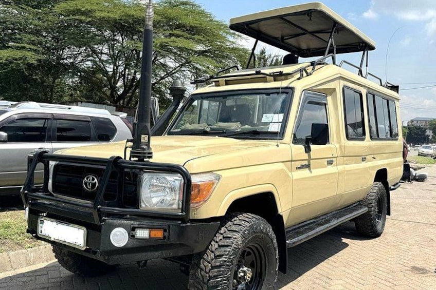 A yellow SUV with off-road tires and a roof rack parked on a paved area. 2