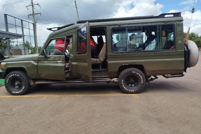 A green off-road vehicle with its door open, parked in a lot. 4