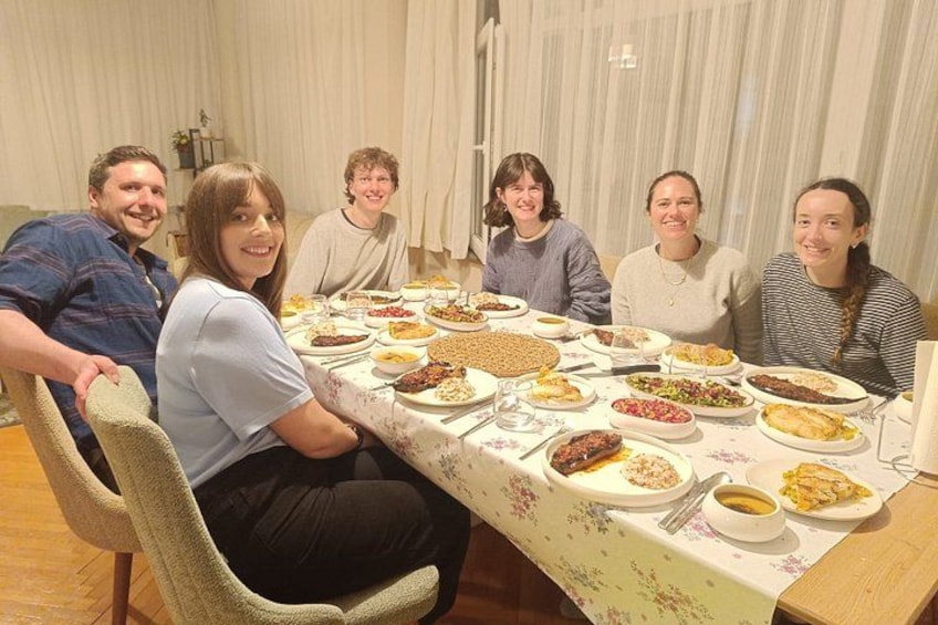 A group of people seated around a table with various dishes. 1